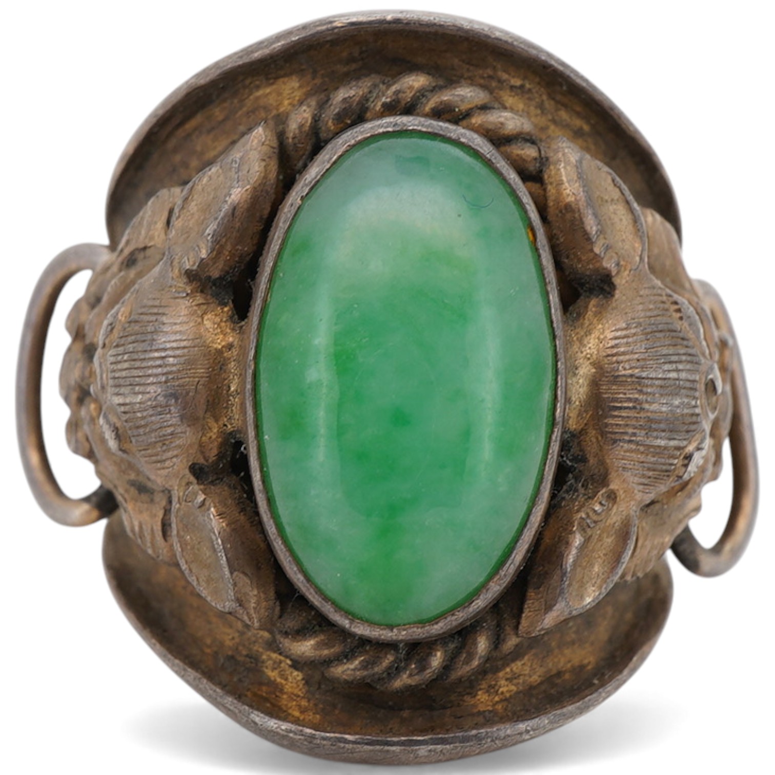 A 20th century Chinese white metal and single stone cabochon jade set ring, the shoulders decorated with lion-dogs, size L.